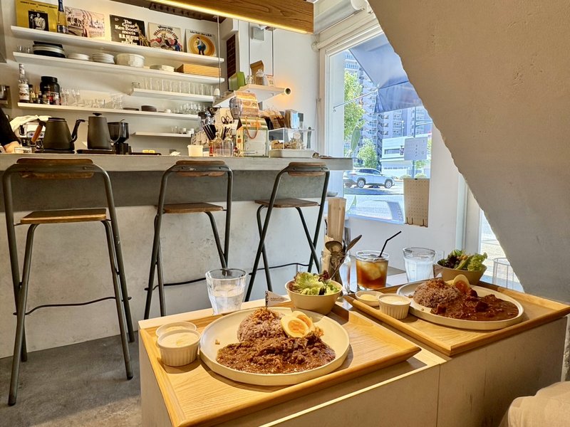 Achim Coffeeの店内。白い壁とコンクリートのカウンター、階段下の席から見た明るい窓辺