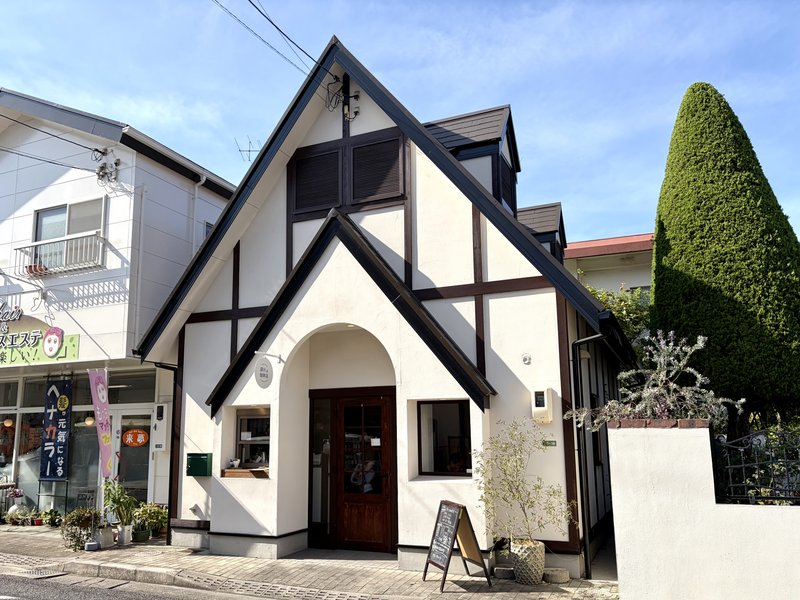 深川珈琲店の外観。青空の下、白い壁に濃茶の柱が入った三角屋根のかわいい建物