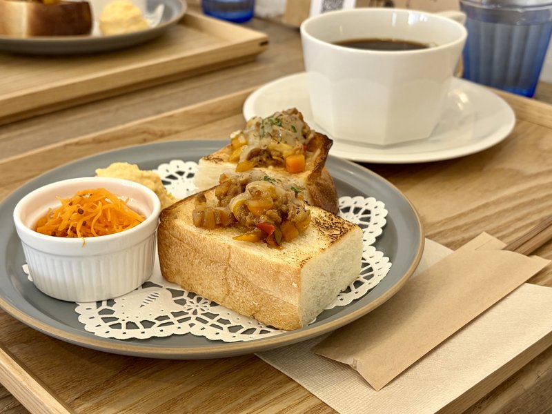 深川珈琲店のモーニングプレート。分厚いトーストにキーマカレーととろけたチーズがのり、白い器にキャロットラペ、奥に玉子ペースト