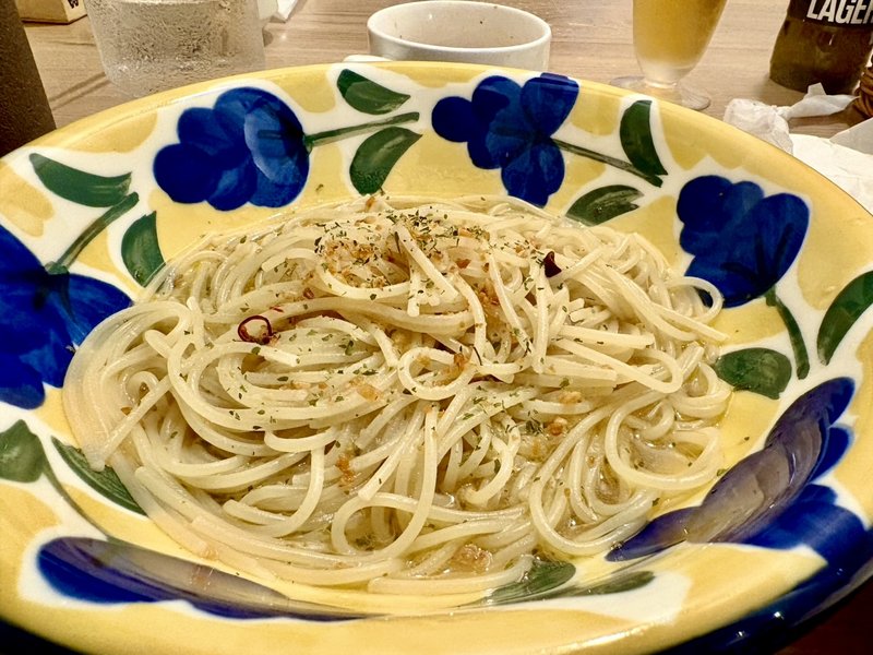 ペコラパスタのにんにく&唐辛子のペペロンチーノ。青い花柄の皿に細めのパスタ、輪切りの唐辛子とガーリックチップ