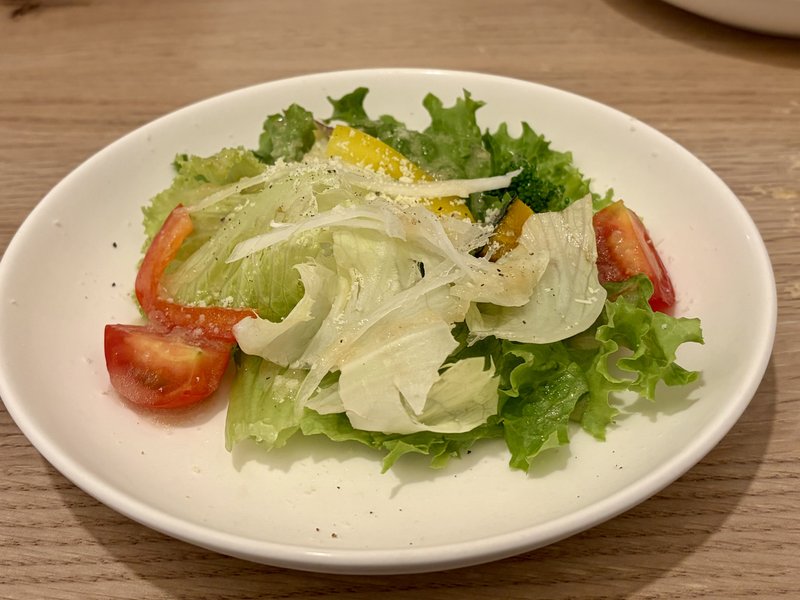 ペコラパスタのランチに付くサラダ。レタスにトマト、パプリカ、スライス玉ねぎ、粉チーズがのっている