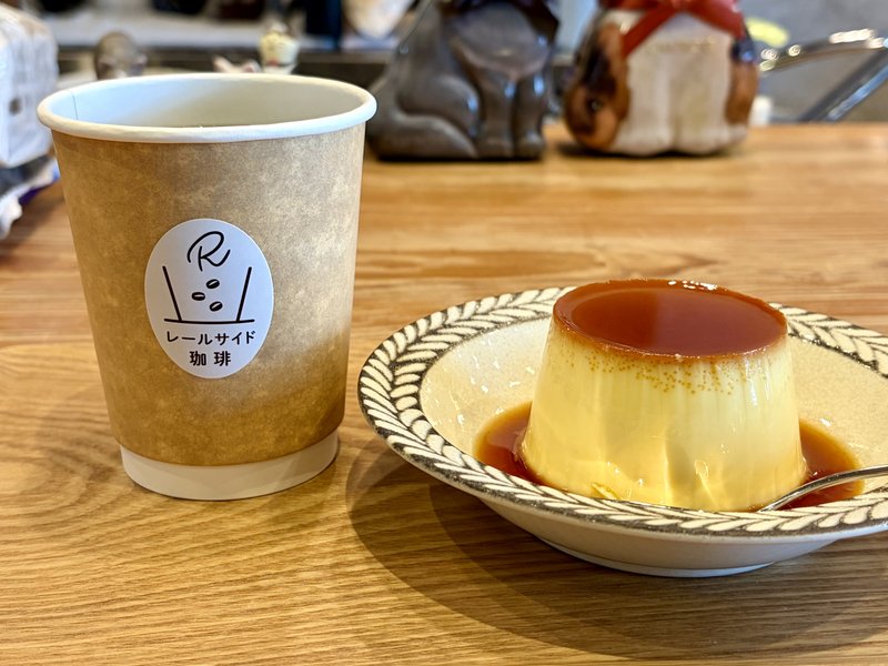 レールサイド珈琲のロゴが入ったカップのコーヒーと、カラメルのかかったプリン