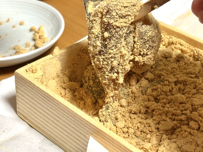黄金わらびのわらび餅をすくい上げたところ。とろとろに柔らかく垂れている